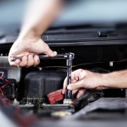 A picture of a mechanic doing some work to a car under the bonnet