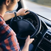 a man driving a car with view of steering wheel and dashboard