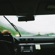 An image of the inside of a car facing the windscreen with the windscreen wipers on