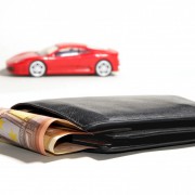An image of a wallet with 50 euros sticking out and a red toy car in the background