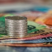 An image of a coin stack atop a pile of notes to signify payment