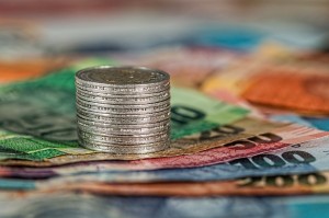 An image of a coin stack atop a pile of notes to signify payment